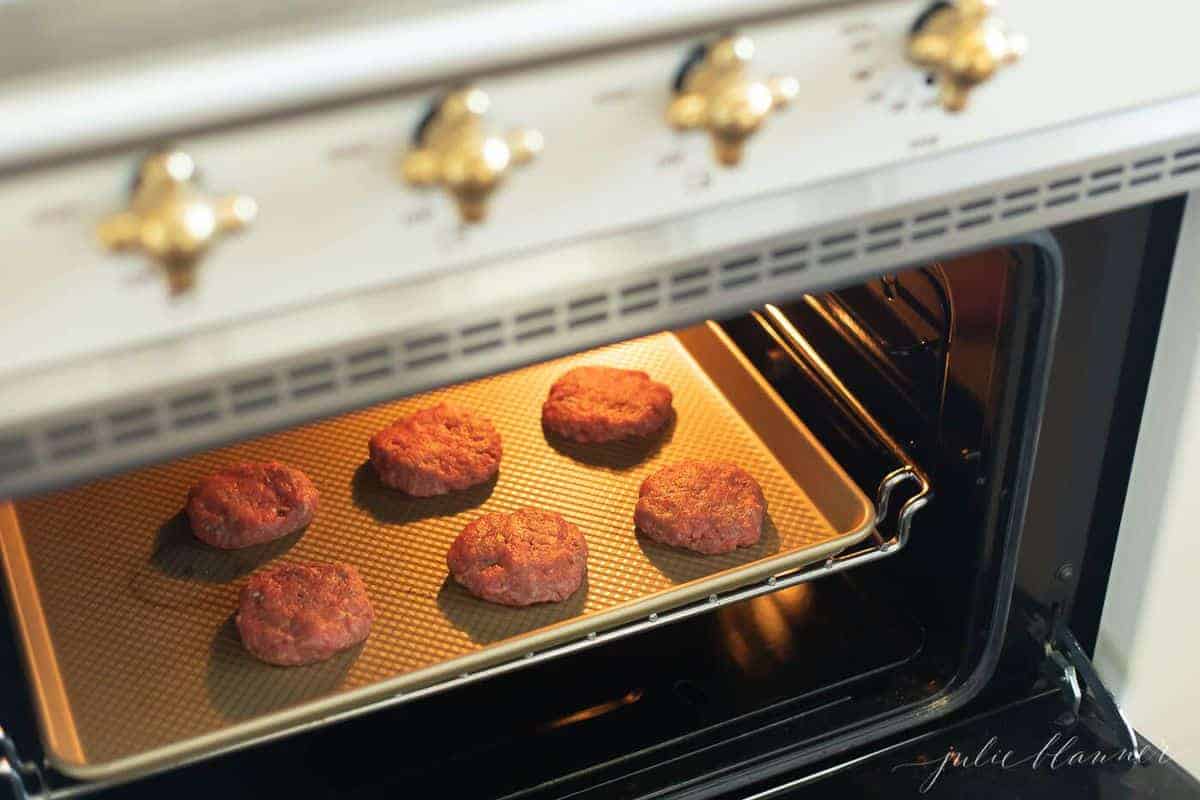 在烤箱的金烘烤板上的六个牛肉馅饼。#sliders #easysliders。GydF4y2Ba