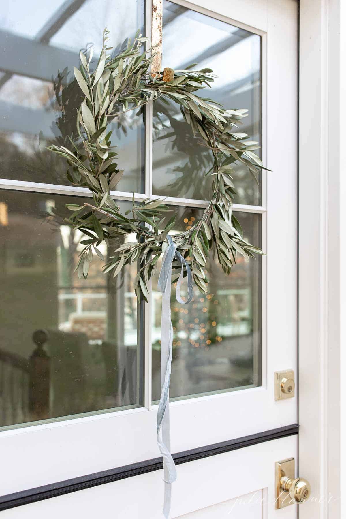 一扇荷兰式门的窗户上挂着一个自制的花环，可以看到为圣诞节装饰的客厅。