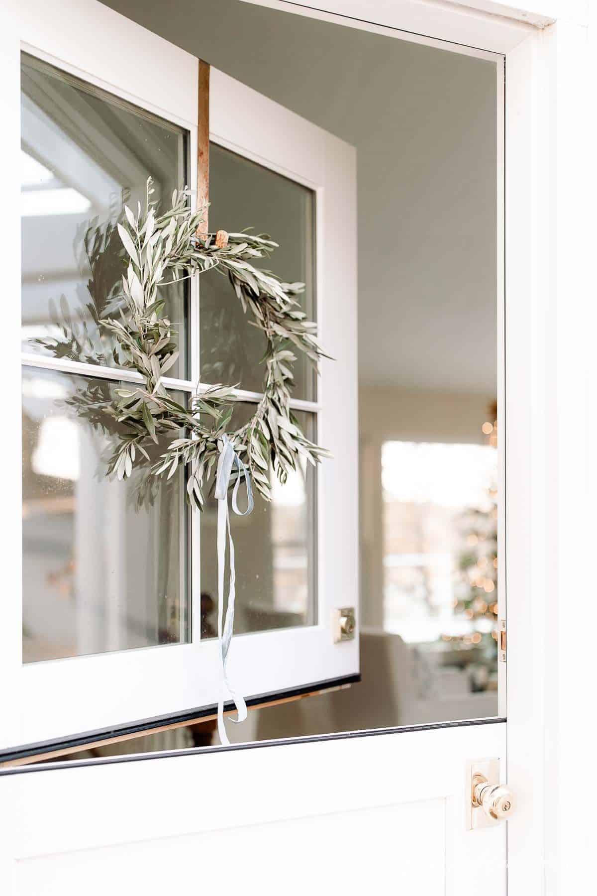 一扇荷兰式的门，窗户上挂着一个DIY的花环，可以看到为圣诞节装饰的客厅。