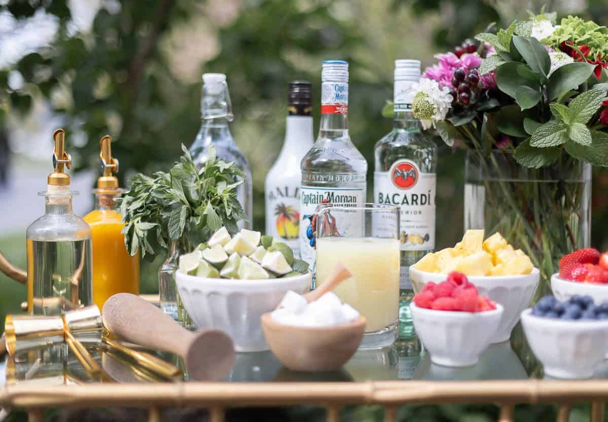玻璃和黄铜酒吧车设置在户外莫吉托酒吧，酒精瓶旁边的碗中的各种水果和酸橙。