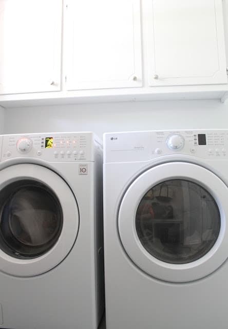 一个洗衣机和烘干机，在带有白色橱柜的泥房洗房间里。