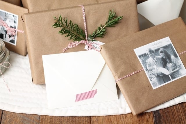 棕色牛皮纸包裹的礼物与面包师的缠绕捆绑，装饰着旧家庭照片和度假绿叶。