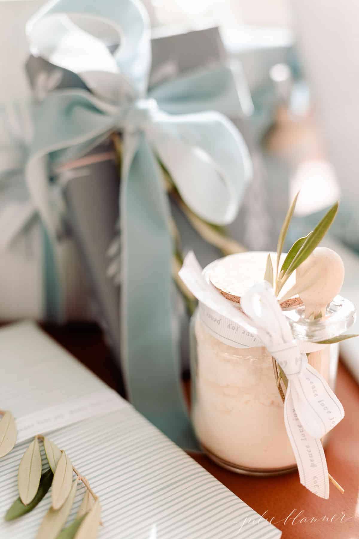 柔软的蓝色和白色的礼物包装下的树，与一个透明的玻璃罐浴盐系一个蝴蝶结。