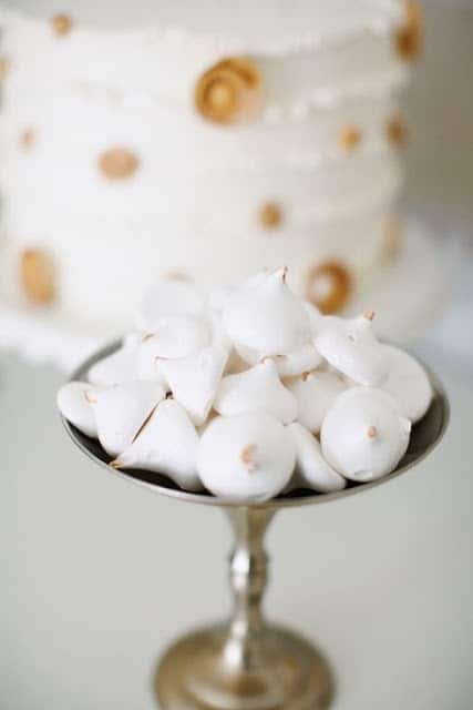 一盘白色饼干在白色和金圆点新年的蛋糕前。