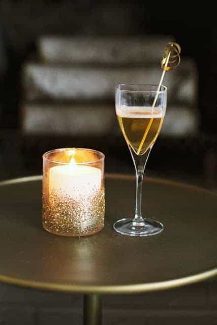 一杯香槟旁边是一杯闪闪发光的蜡烛。