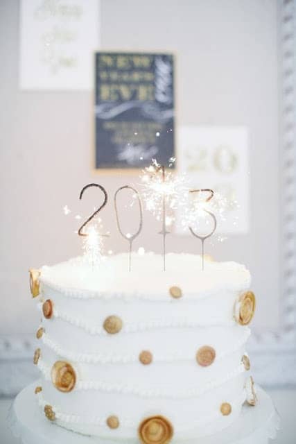 白色和金圆点新年前夕蛋糕，上面放着2013年的烟火蜡烛。