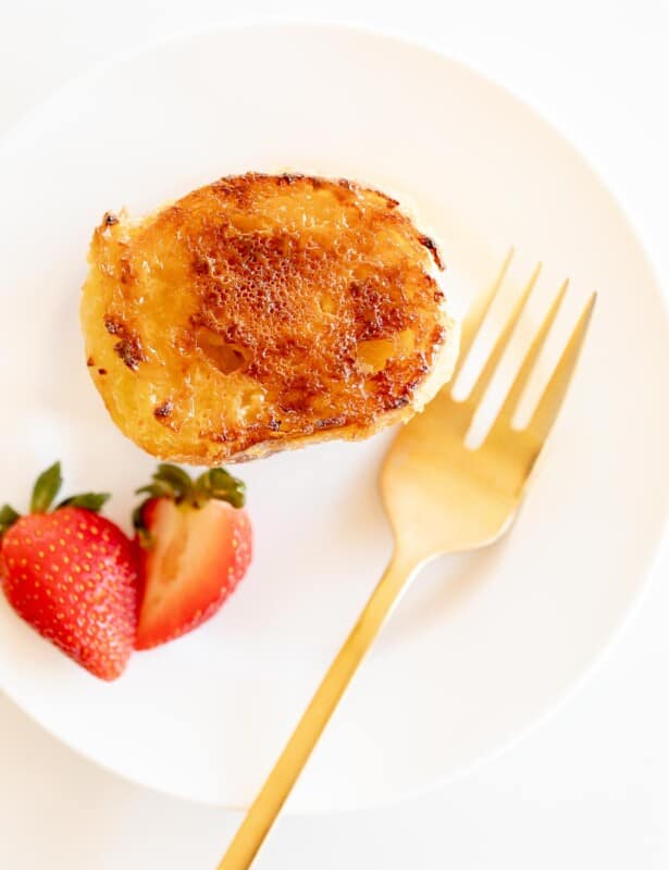 切片在白色板材的奶油奶油法国多士用金叉子和草莓