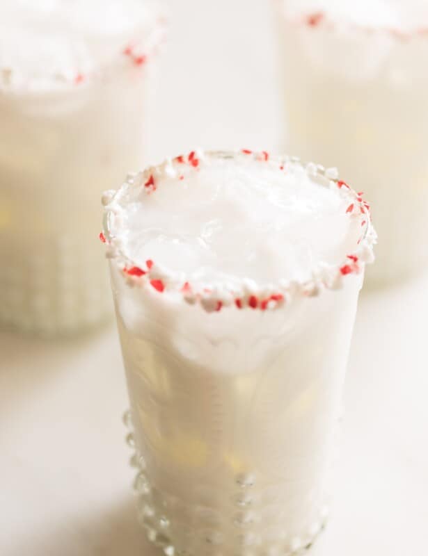 透明玻璃杯中的奶油白色鸡尾酒，饰有压碎的薄荷。