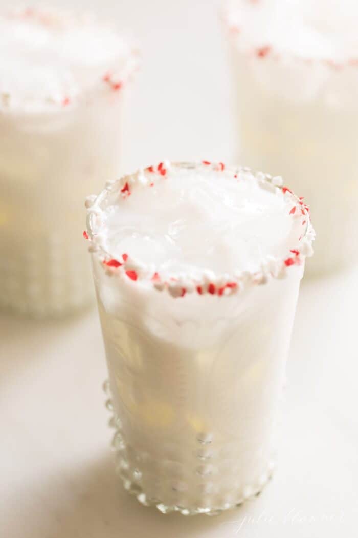 一杯奶油白色鸡尾酒，盛于透明玻璃杯中，杯沿镶有碎薄荷。