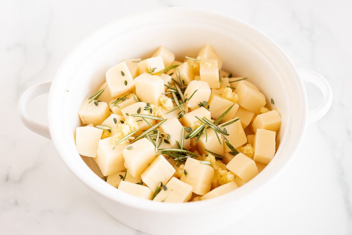 切碎的fontina奶酪放在白色的碗里，上面撒上新鲜的香草gydF4y2Ba