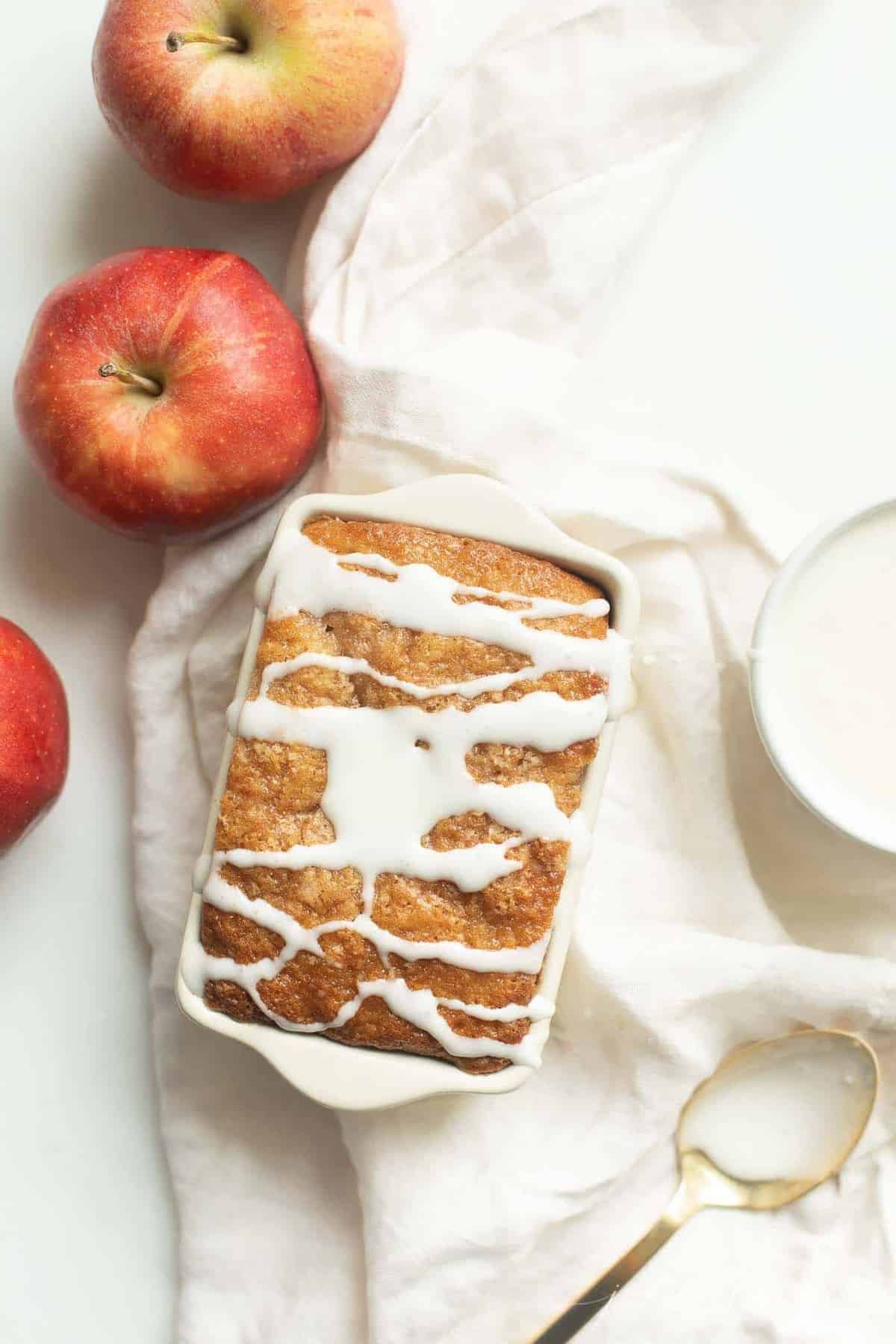 一小盘苹果面包，上面涂上白色糖霜，周围放上苹果和亚麻餐巾。gydF4y2Ba