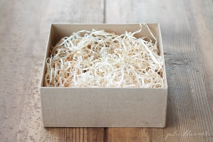 一个牛皮纸纸盒，里面有一块软木切碎的饼干包装教程。