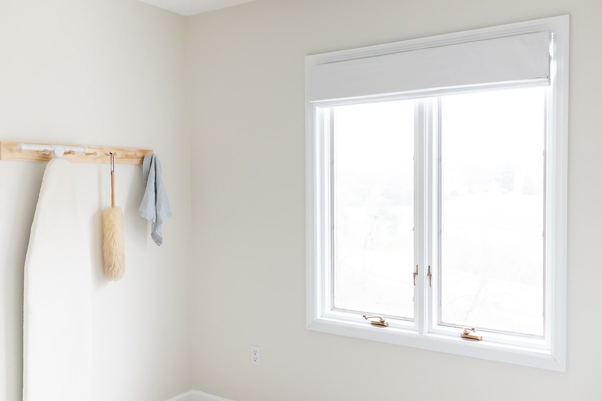 洗衣房储物间挂钩栏杆旁的窗户上有白色的罗马窗帘