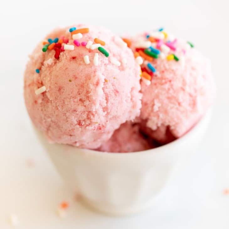 一碗白碗草莓雪冰淇淋，上面撒上彩虹。GydF4y2Ba