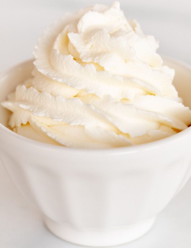 一个白色的碗，里面装满了大理石表面上的鲜奶奶油霜。