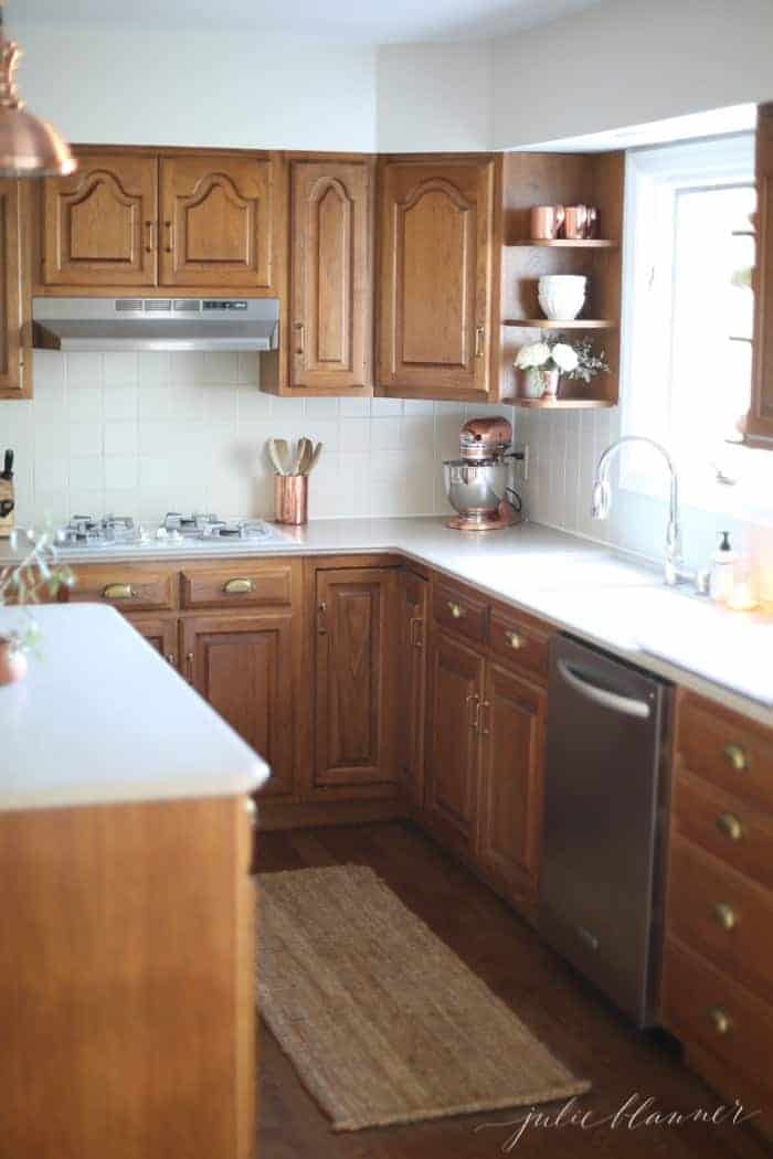 一个现代化的厨房，橡木橱柜，新鲜的白色油漆，黄麻地毯，和铜的口音。