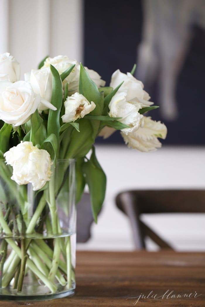 一个装满白色郁金香的花瓶放在早餐角落的桌子上。