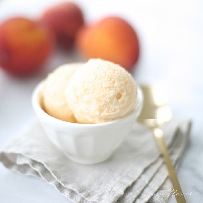 不要把桃子冰淇淋放在白色的碗里，碗里放着桃子，旁边放着一个金勺子。