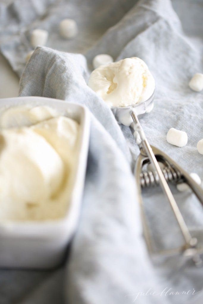 一个装满棉花糖冰淇淋的白面包平底锅，一勺冰淇淋，边上放着迷你棉花糖。