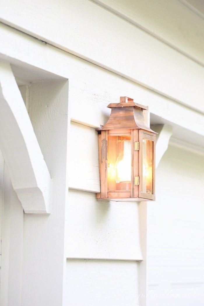白色的房屋外观，车库门之间有一盏铜制灯笼。