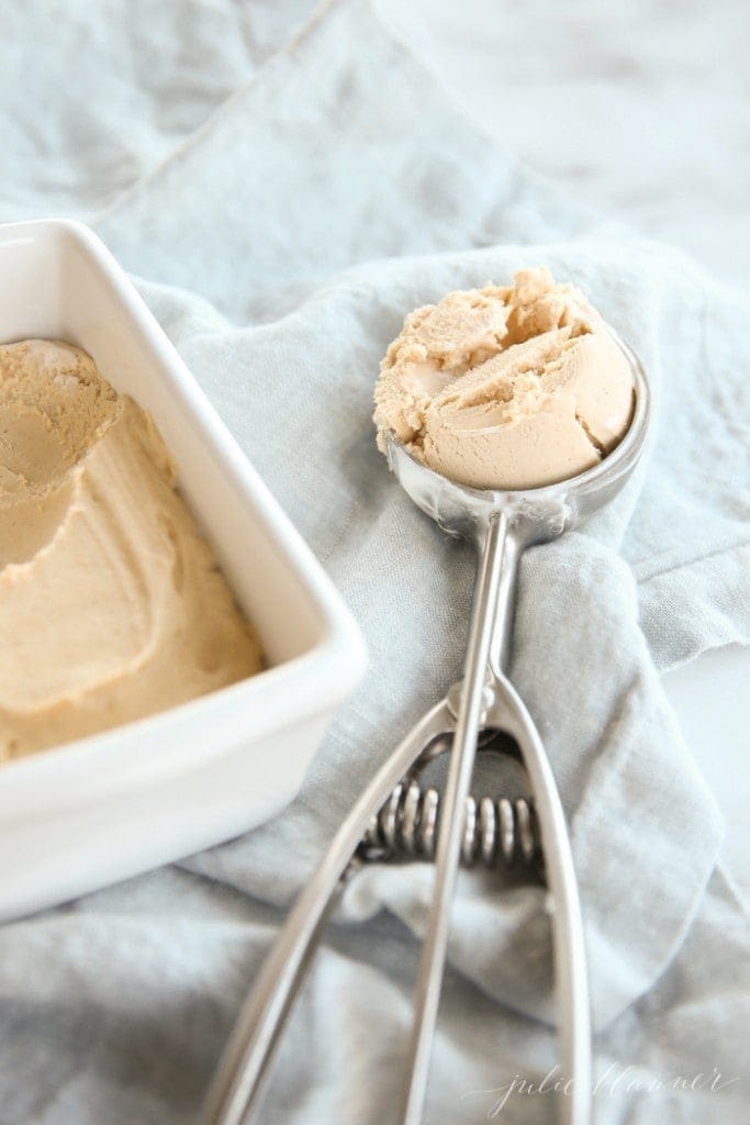 一个装满自制冰淇淋的白面包平底锅，旁边放一勺冰淇淋。