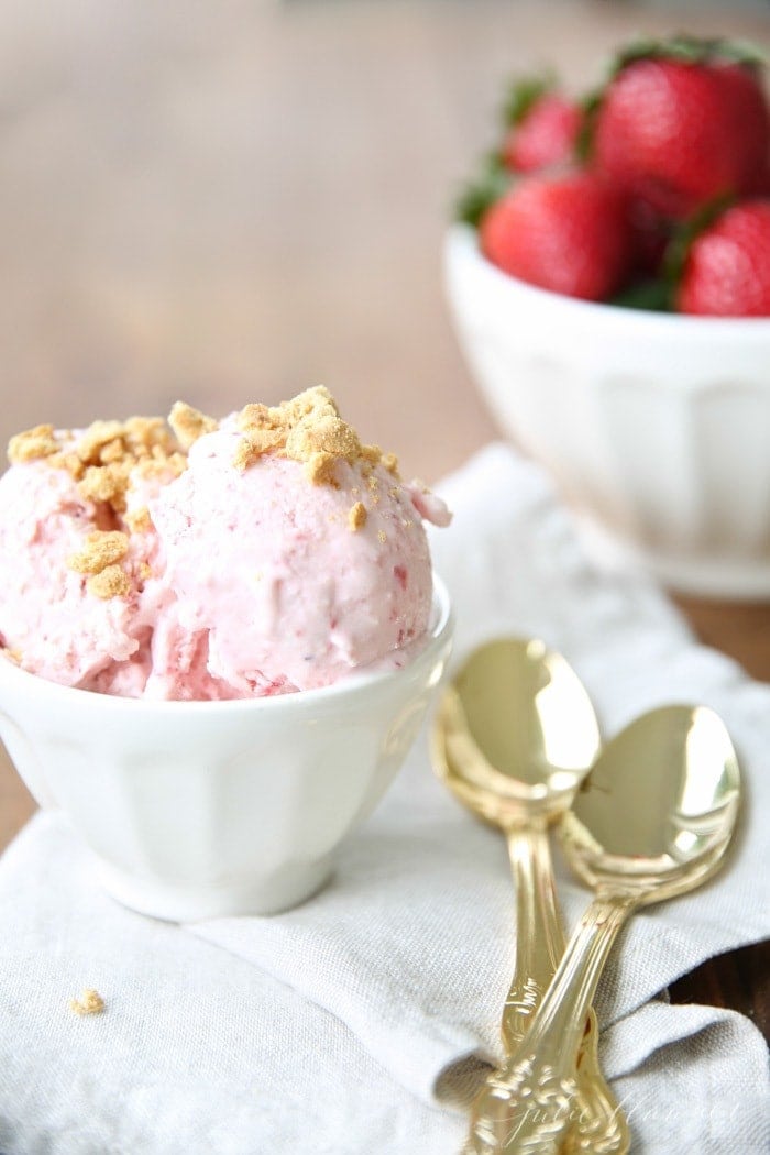 草莓芝士冰淇淋装在一个白色的碗里，旁边放着两个金勺子。