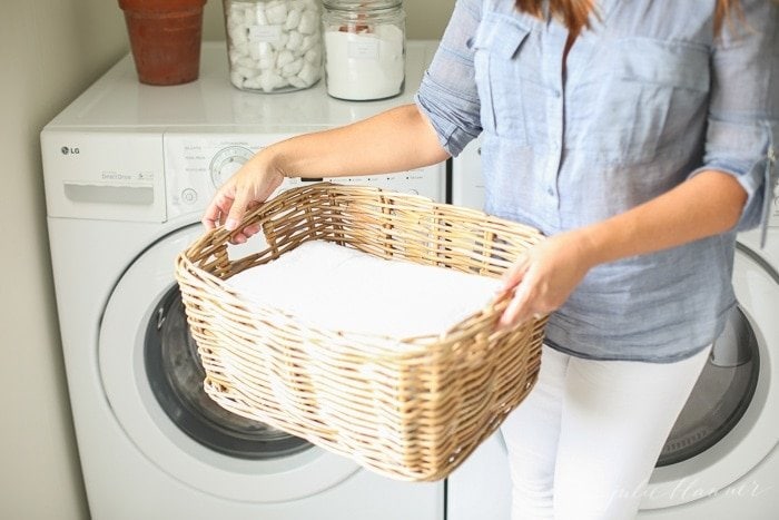女人提着洗衣篮在洗衣机前