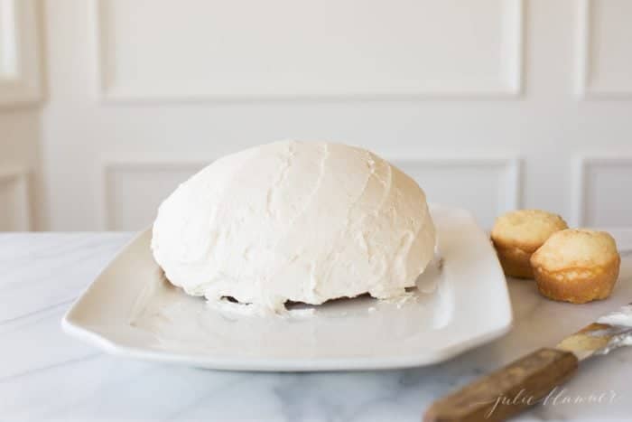 在白色浅盘上撒上白色糖霜的圆形蛋糕，做成复活节兔子蛋糕。gydF4y2Ba