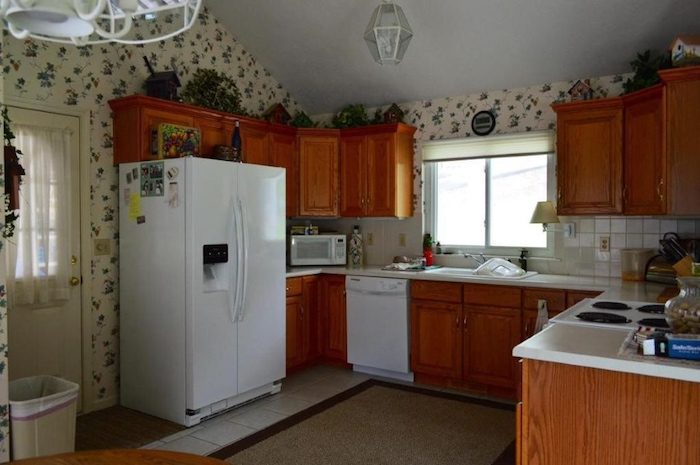 湖畔小屋前的厨房。厨房有橡木橱柜和花卉墙纸。