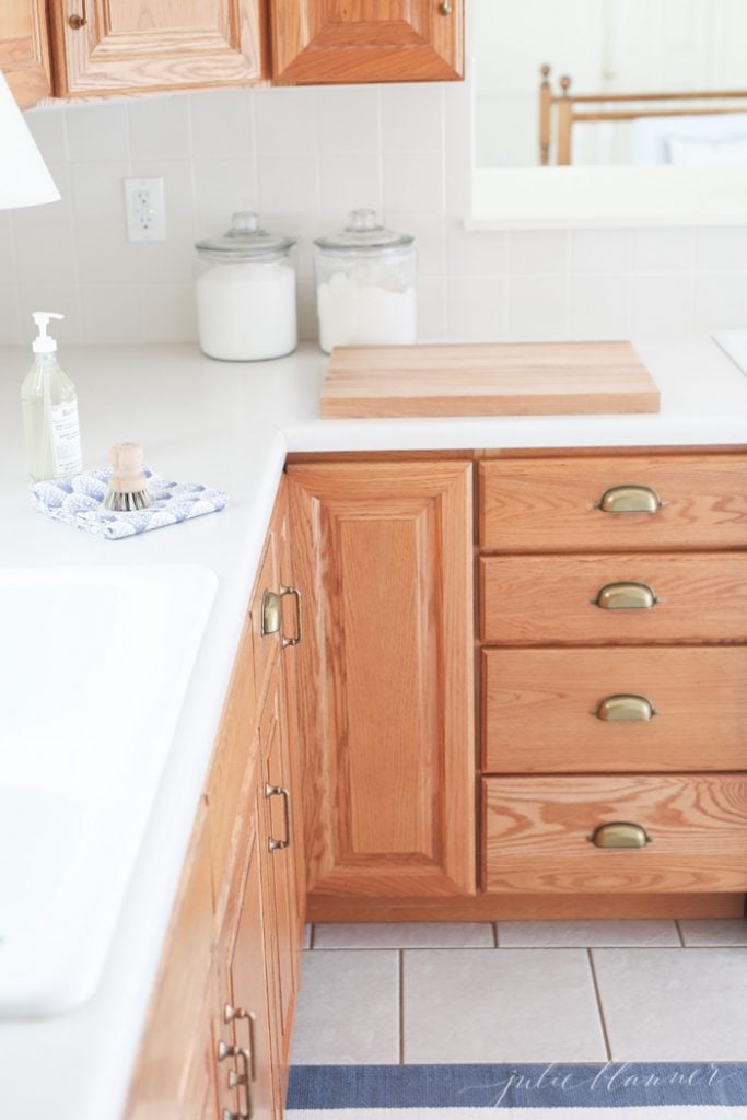 用新的橱柜硬件很容易让陈旧的厨房变得现代。橡木橱柜与温暖的黄铜橱柜拉和杯拉看起来很漂亮。
