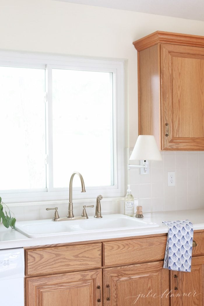 台子上有扇形的青花餐具布，靠近瓷质水槽。用橡木橱柜装饰厨房是一种简单的方法。