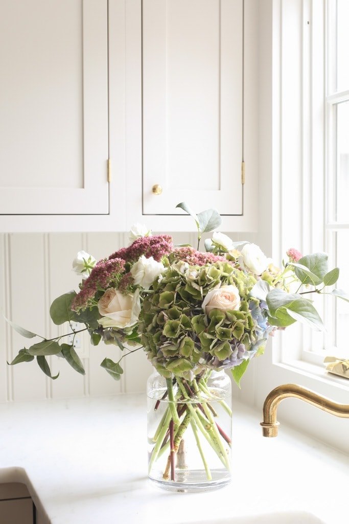 厨房白色窗户旁的玻璃花瓶里插着一束简单的秋花。
