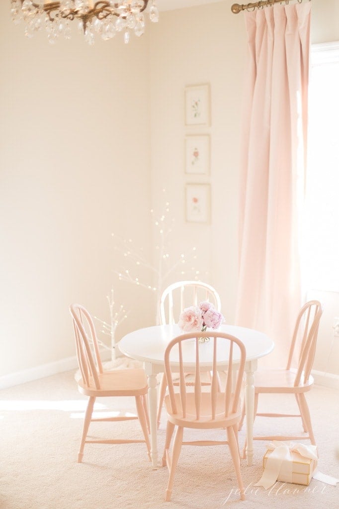 一个女孩的卧室，有粉红色的遮光窗帘和小桌椅。