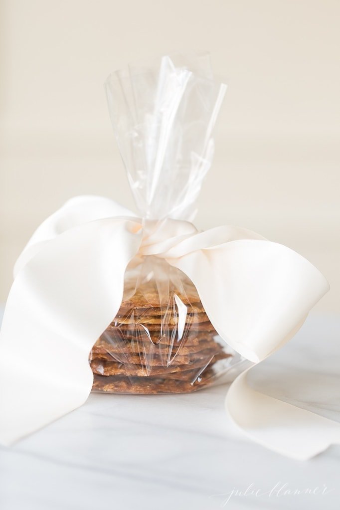 用玻璃纸和丝带包裹的燕麦蕾丝饼干堆叠在大理石表面gydF4y2Ba