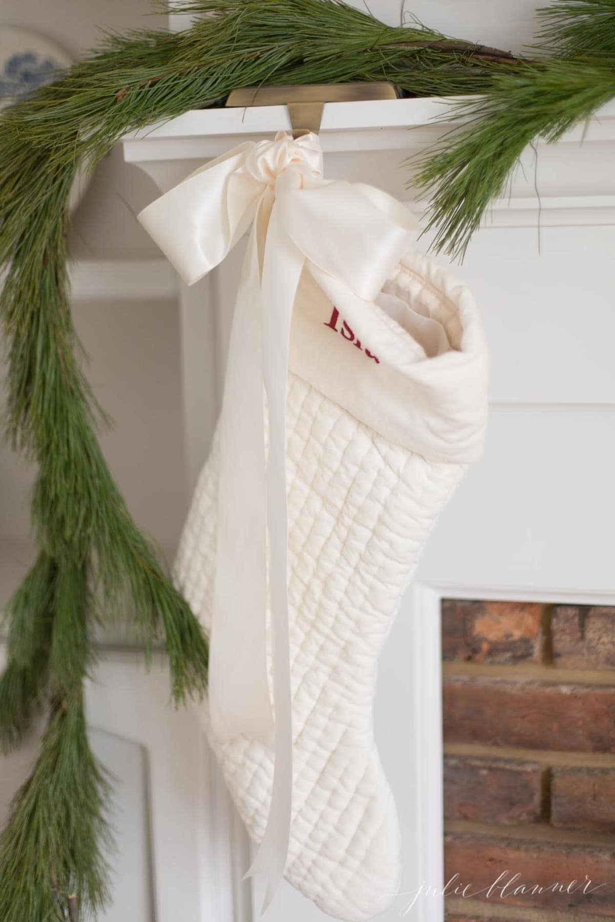 一个砖砌的壁炉，白色的壁炉架和一个绿色的花环，上面挂着圣诞袜