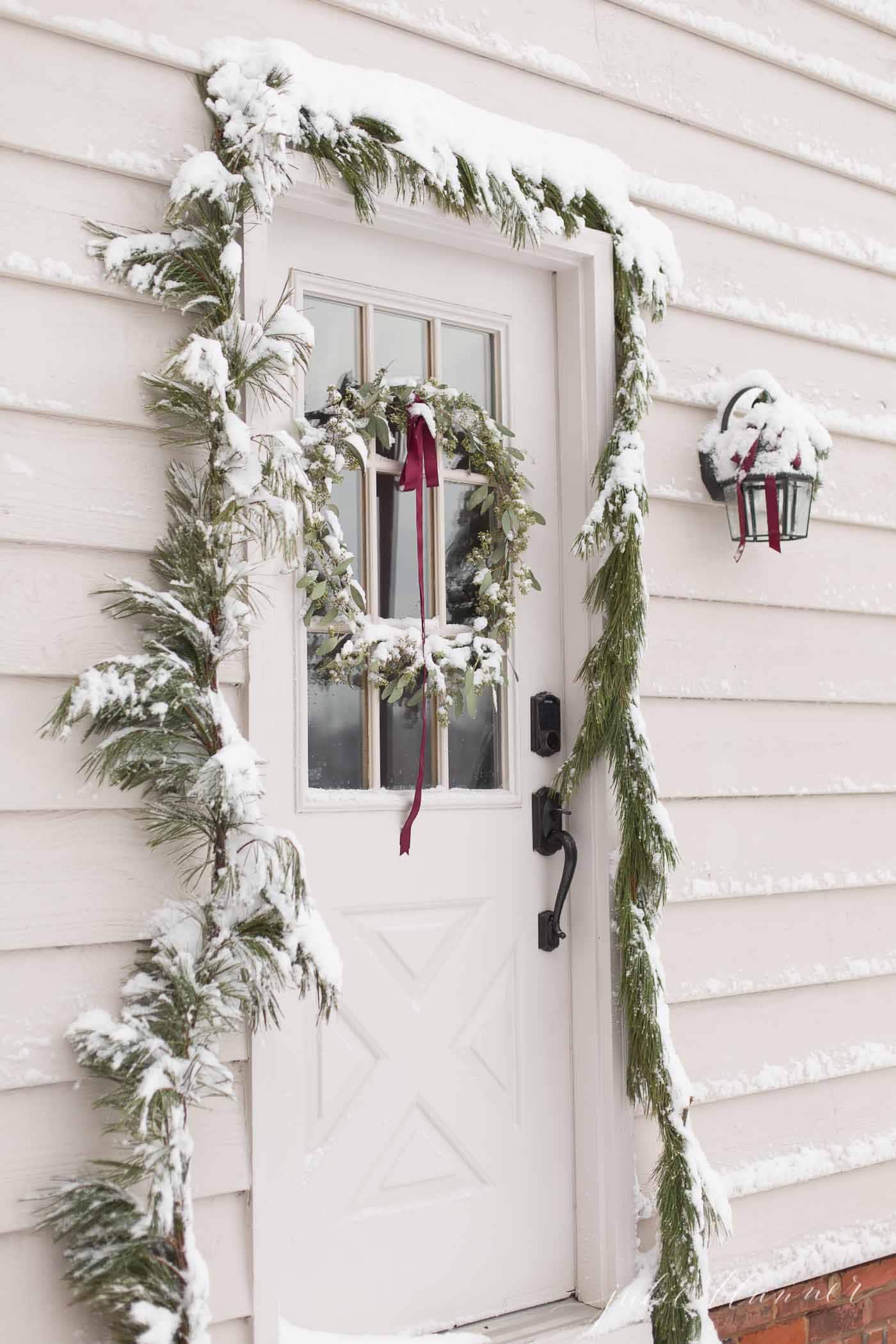 圣诞门上有一个自制的花环和花环，上面覆盖着雪