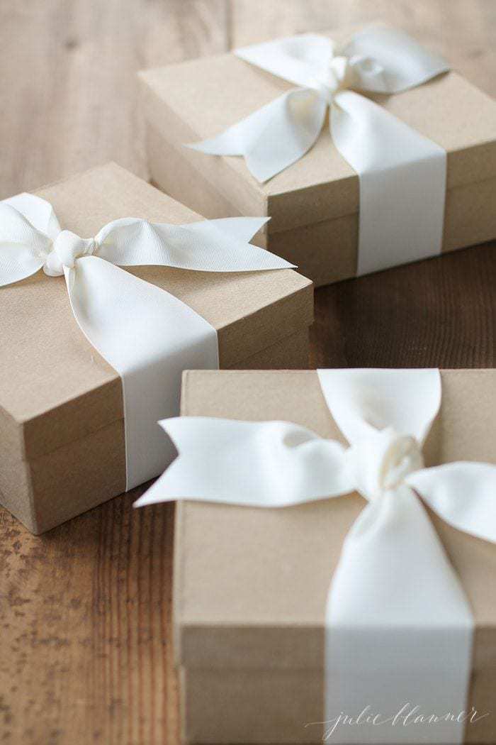 木制表面用牛皮纸棕色盒子，白色丝带包装自制圣诞礼物。