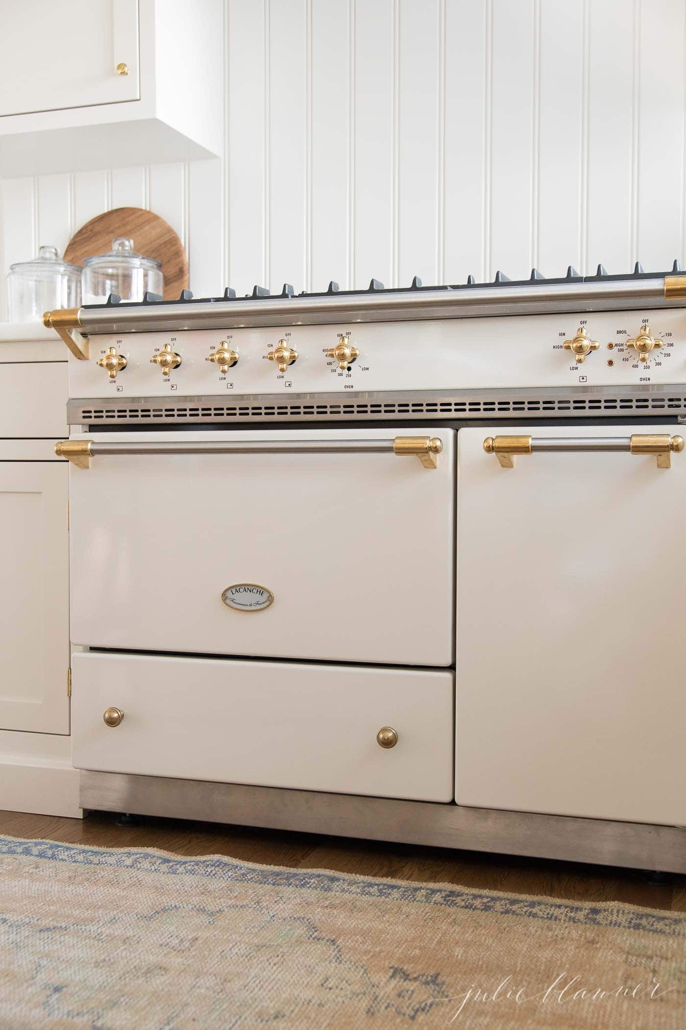 奶油白色的厨房里有一个法式炉灶，后挡板有床头板