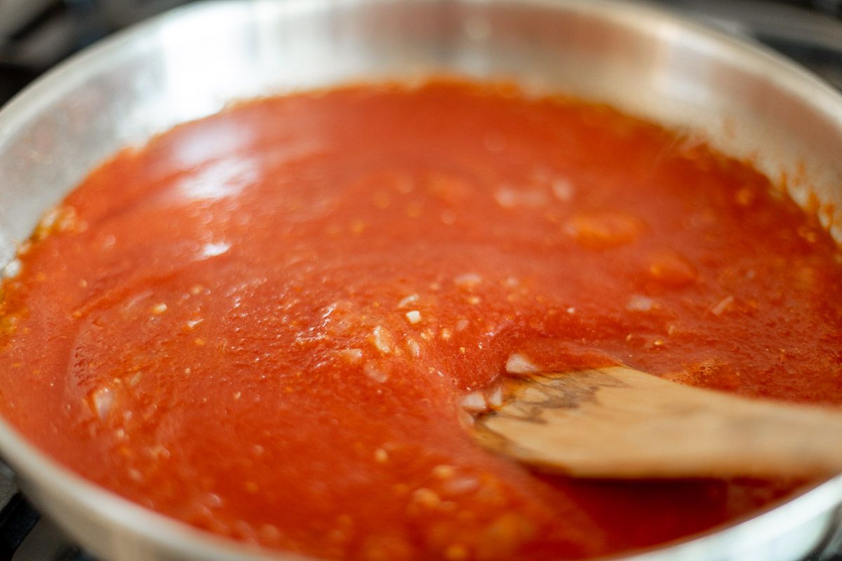 在炉灶上煮番茄酱，木勺放在旁边。gydF4y2Ba