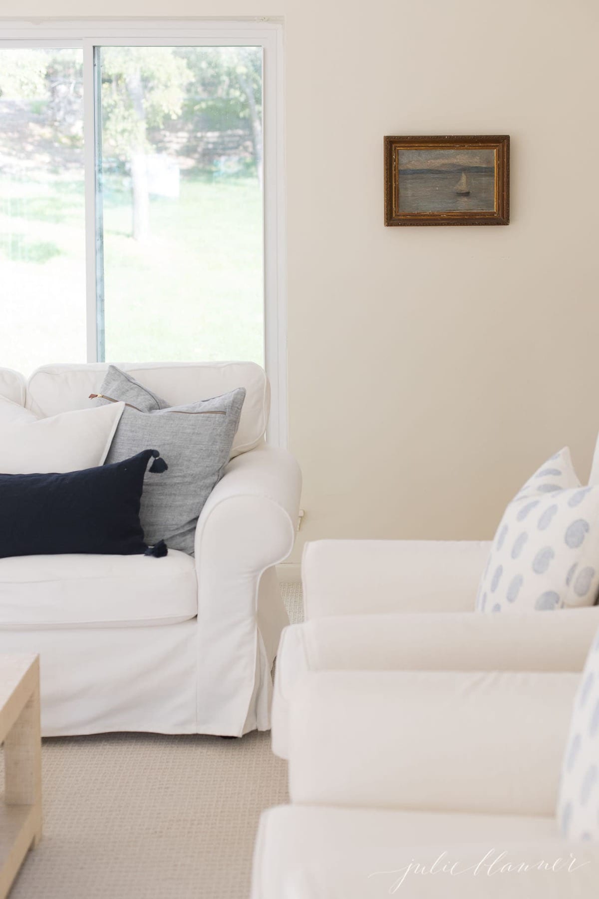 一个白色房间，带有象牙色的家具，装饰枕头上的蓝色枕头盖。