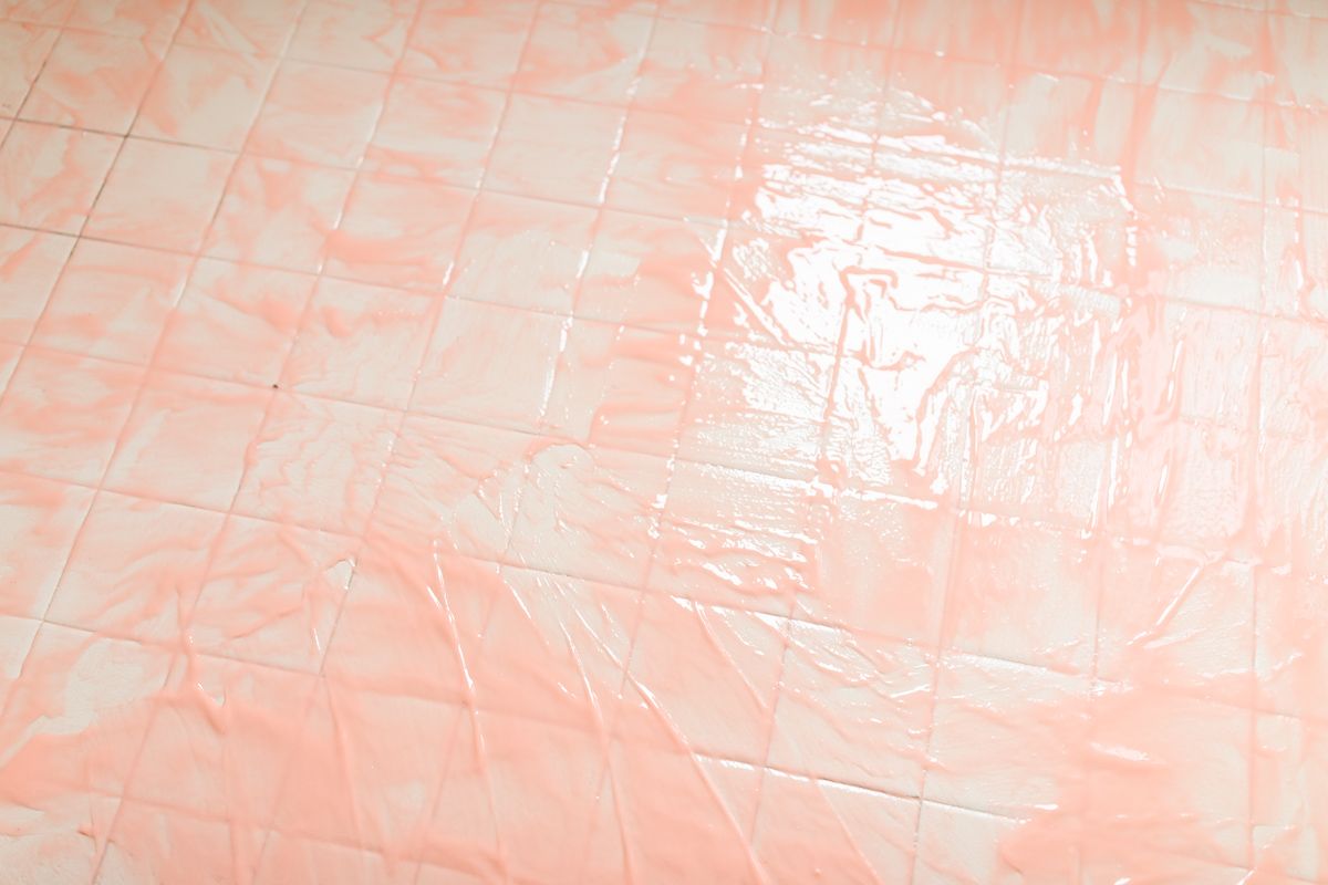 有人把粉红色的柑橘条涂在旧的浴室瓷砖上。