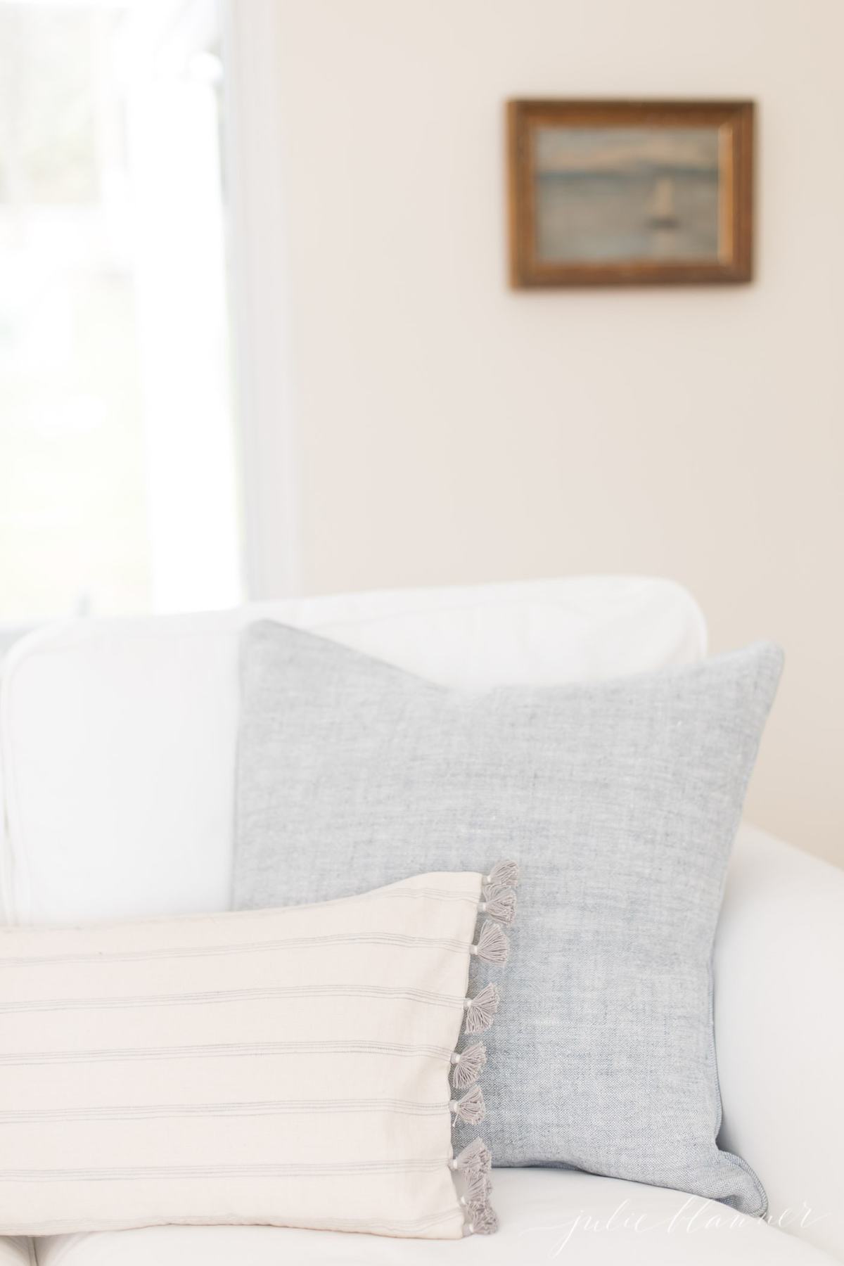 客厅里的白色沙发配蓝色枕头，在一篇文章中讲述了一种简单的去除烟味的方法