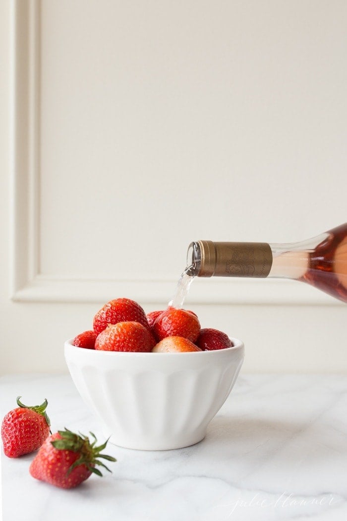 一碗草莓，上面倒着一瓶酒。