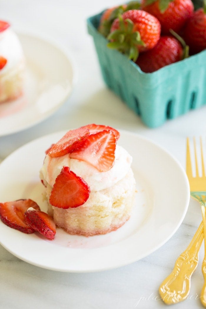 一个装满草莓酥饼的白色碗，背景是一盒草莓。