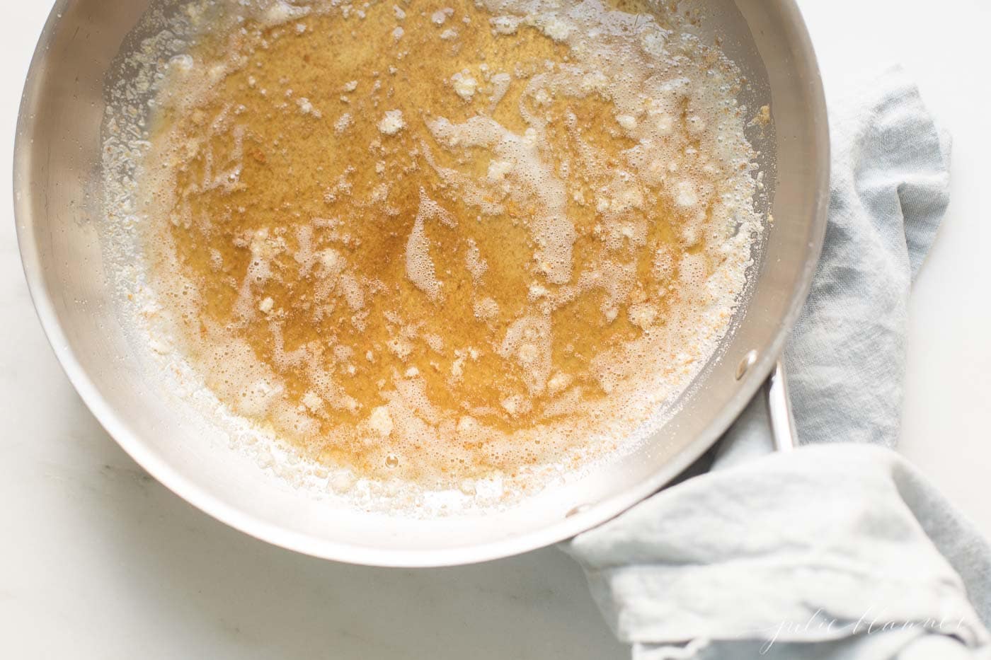一个银色平底锅用柄，里面暖褐色的黄油，显示如何棕色黄油。GydF4y2Ba