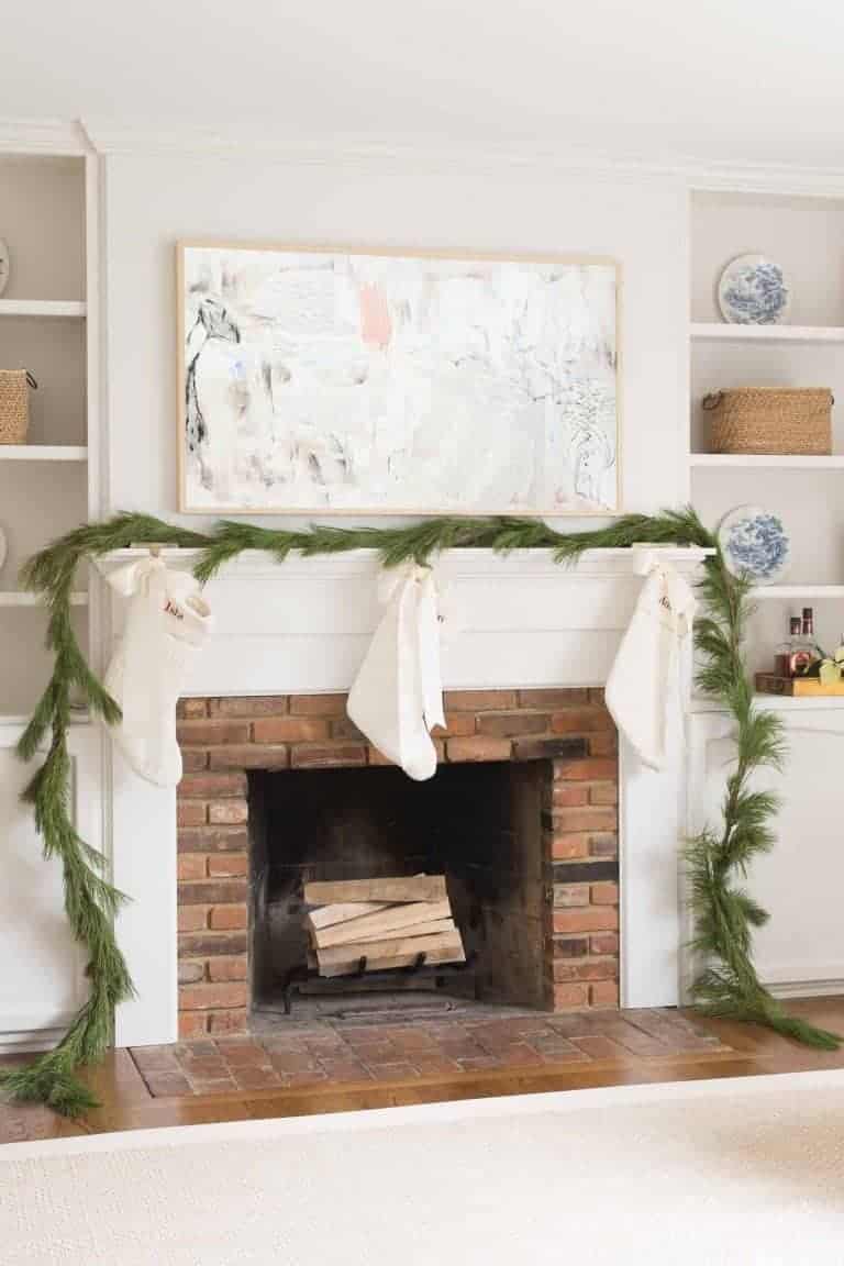 一个装饰有圣诞蔬菜的砖壁炉，带有定制的剑麻地毯，在家庭客厅的地板上有边界。
