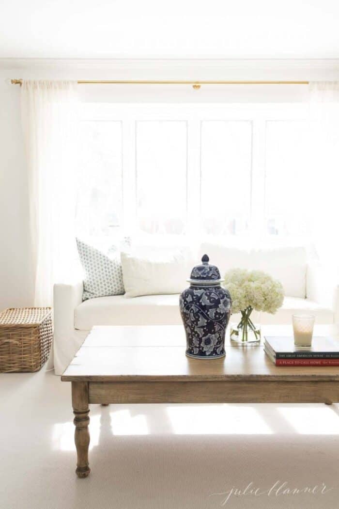 一个白色客厅，有白色的沙发，奶油地毯和木制咖啡桌。