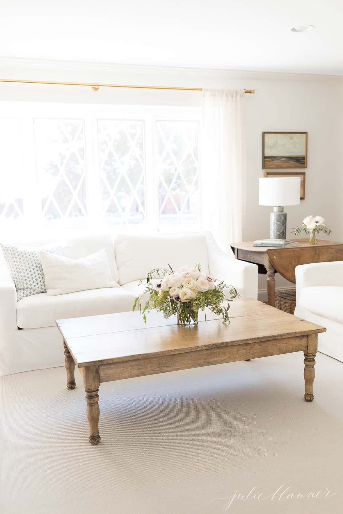 一个白色客厅，有白色的沙发，奶油地毯和木制咖啡桌。