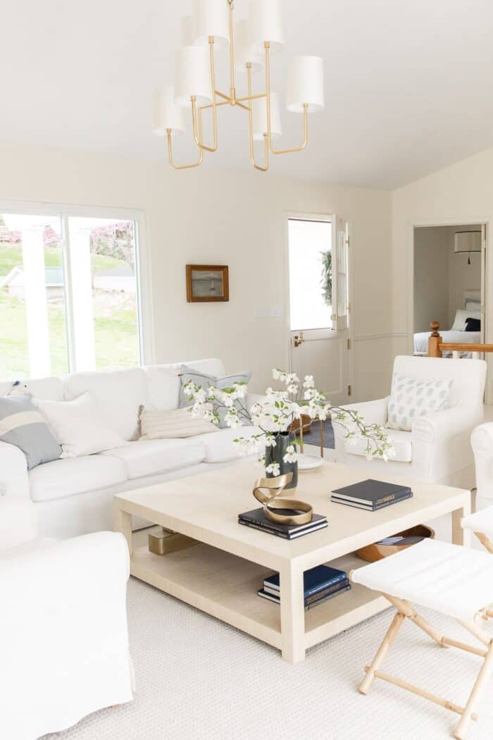 沿海现代客厅，配备白色家具和黄铜吊灯。