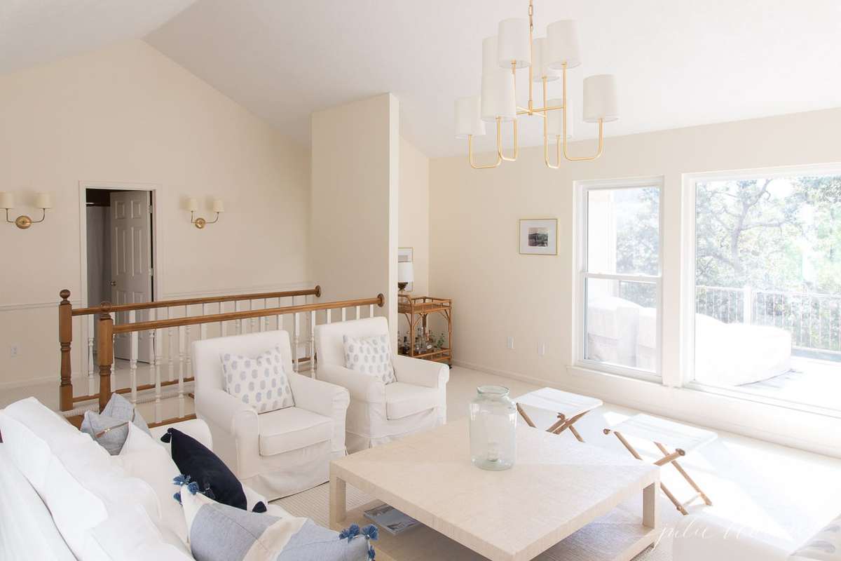 白色家具，蓝色枕头，草布风格的咖啡桌，在现代海滨客厅。
